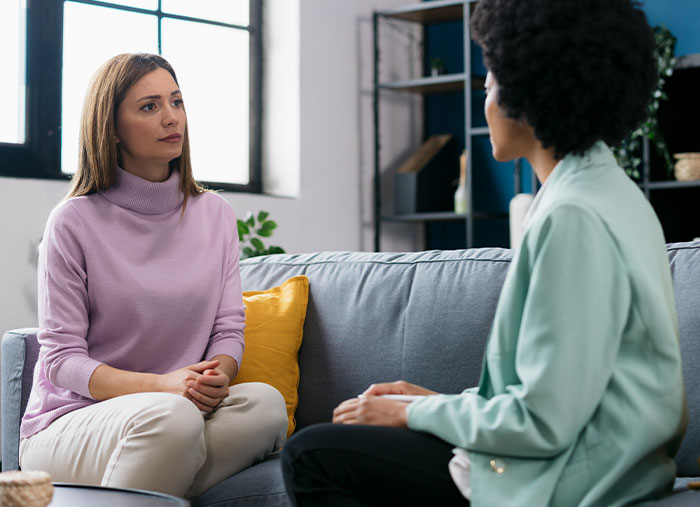 Two women in a deep conversation on a sofa, illustrating moments in great friendships.
