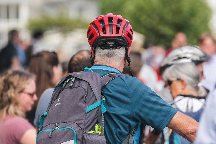Person with red helmet and backpack in a crowd, highlighting first responders' safety awareness.