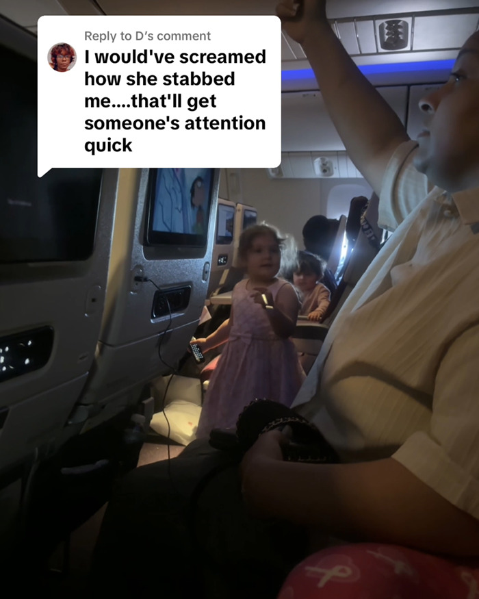 Passenger on flight confronted by child in aisle holding fork, mother asleep nearby.
