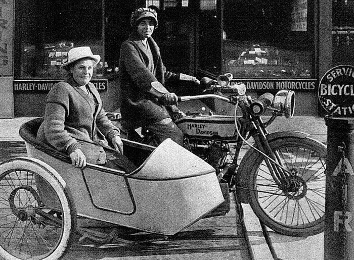 A vintage Harley Davidson motorcycle with sidecar in front of a store, illustrating a fascinating story from history.