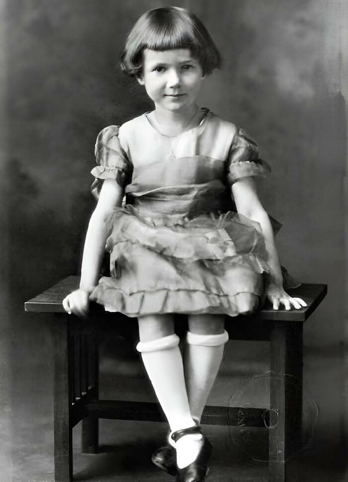 Young girl in vintage dress sitting on a bench, reminiscent of forbidden stories from the past.