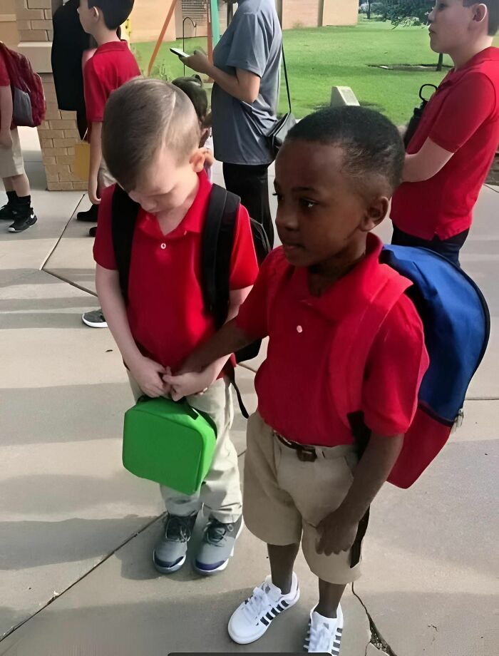 Two children in red shirts and backpacks hold hands, symbolizing a story of friendship and support.