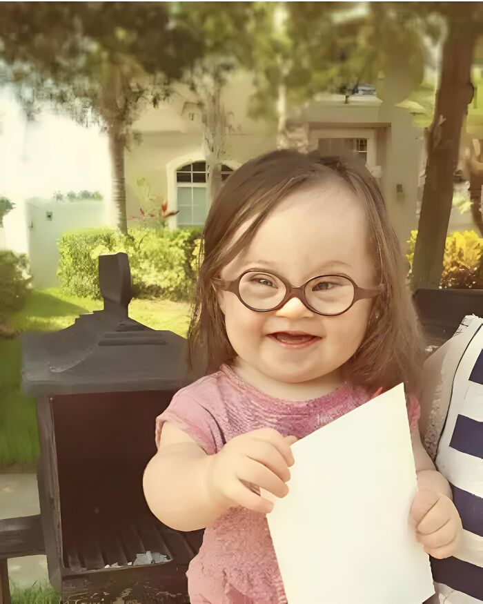 Smiling child in glasses holding paper, representing forbidden stories theme of joy and discovery.