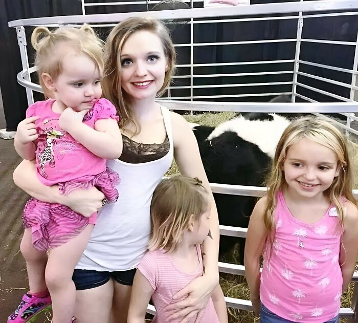 A smiling woman with three children at a petting zoo, showcasing one of many fascinating forbidden stories.