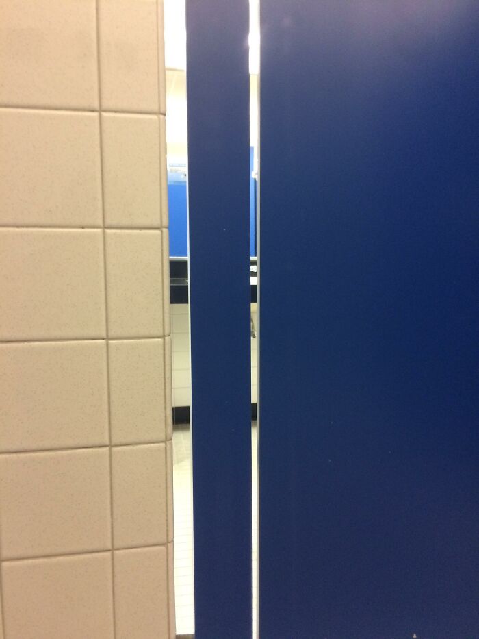 Bathroom stall with gap in the door, illustrating a common culture shock in USA public restrooms.