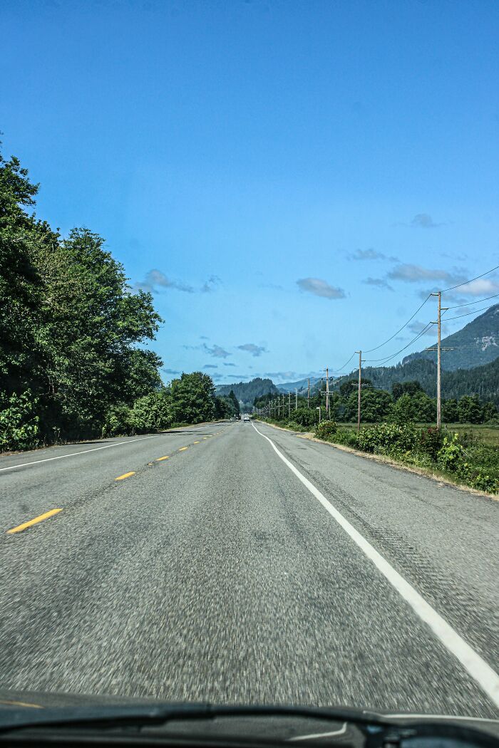 Open road in USA with mountains and trees, a possible culture shock for travelers.