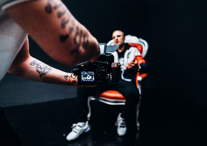 Person filming an anonymous celebrity seated in a chair, capturing a candid confession moment.