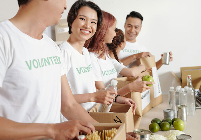 Volunteers packing food boxes, smiling and collaborating at a charity event.