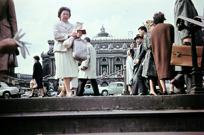 Crowd of people walking in front of historic European building, capturing everyday life in Europe 100 years ago.