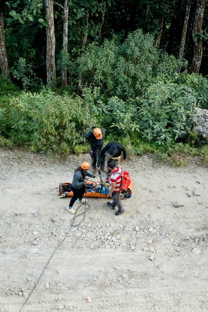 EMTs and first responders handle a stretcher with safety equipment on a dirt path.