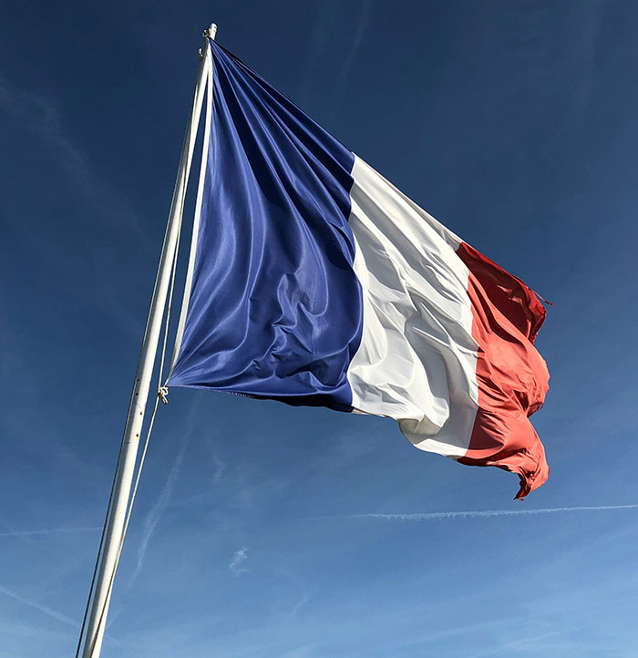 French flag waving against a blue sky, symbolizing national pride and unity. French flag waving against a blue sky, symbolizing national pride and unity.