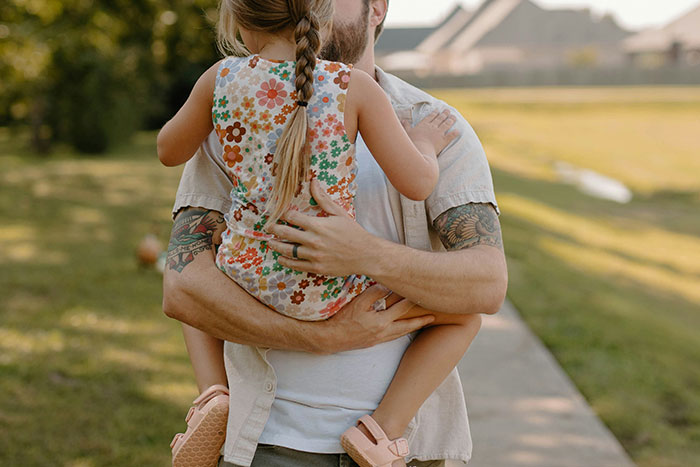 Man holding a young girl outdoors, focusing on the theme of babysitting.