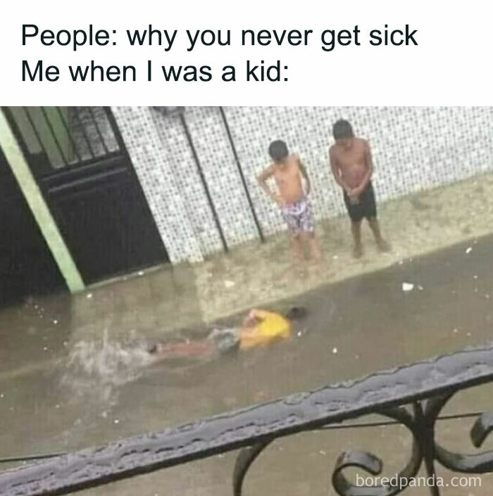 A boy swimming in a flooded street, while two others watch, humorously showing why some men never get sick as kids.