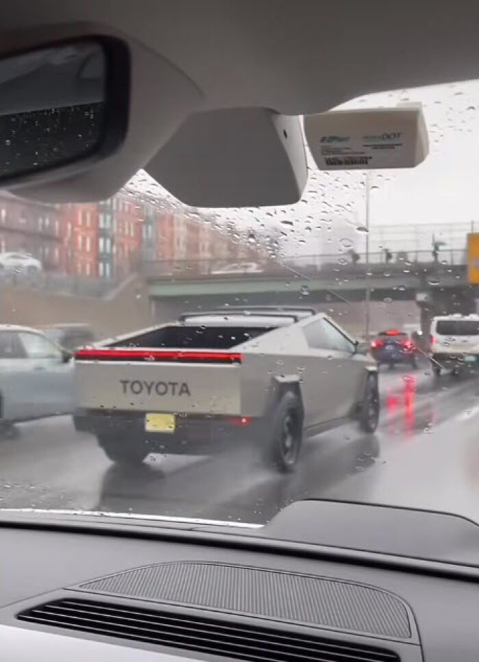 A car designed to resemble a futuristic truck labeled "Toyota" driving in the rain, showcasing a confident fail.
