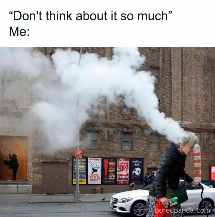 Woman humorously aligned with steam from a vent, creating a meme-worthy scene on the street.