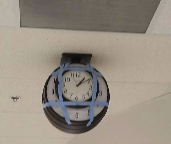 Clock taped to ceiling in a failed repair attempt, showcasing an unusual fix.
