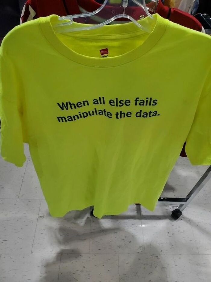 Camiseta amarilla divertida y ridícula con frase en inglés colgada en percha en tienda pública.