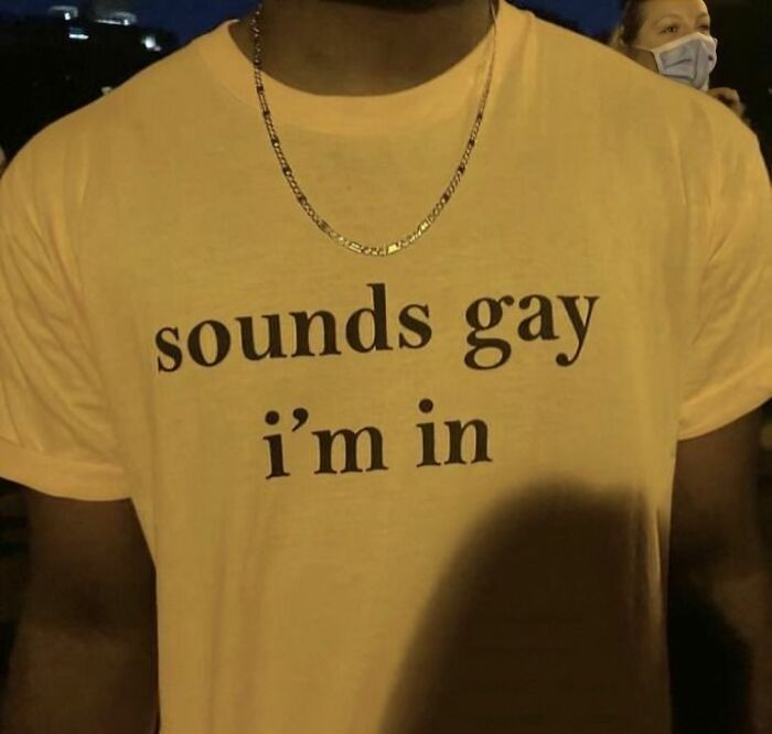 Hombre con camiseta divertida y ridícula en color amarillo con texto en inglés en un ambiente nocturno.