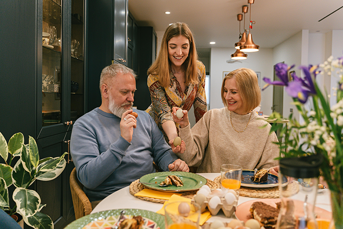 Family at breakfast, discussing assets for biological kids, woman smiling, vibrant kitchen setting.