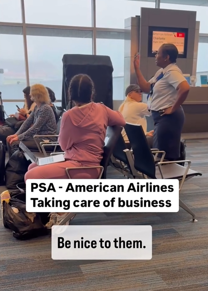 Airline worker addressing passengers at airport after delay, gesturing confidently while seated passengers listen attentively.