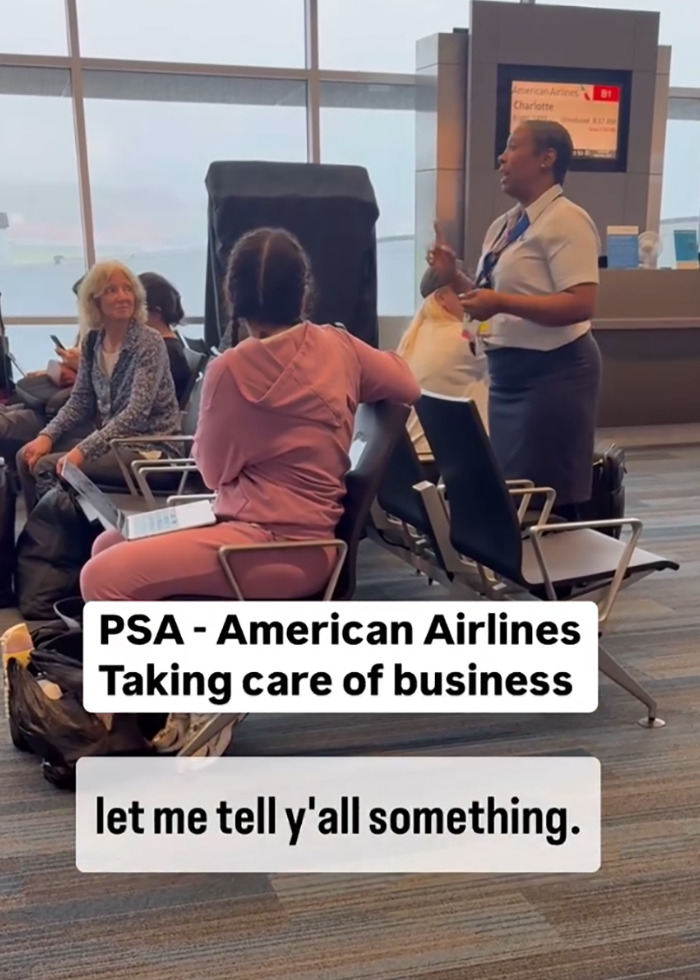 Airlines worker gives speech to passengers after delay, standing in terminal near seated travelers.