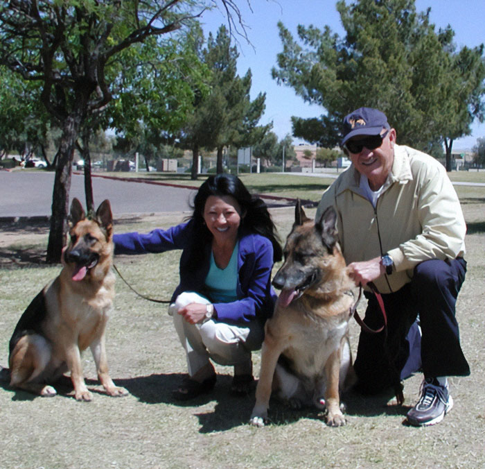 Two people with German Shepherds in a park, linked to new police footage involving Gene Hackman's dog.