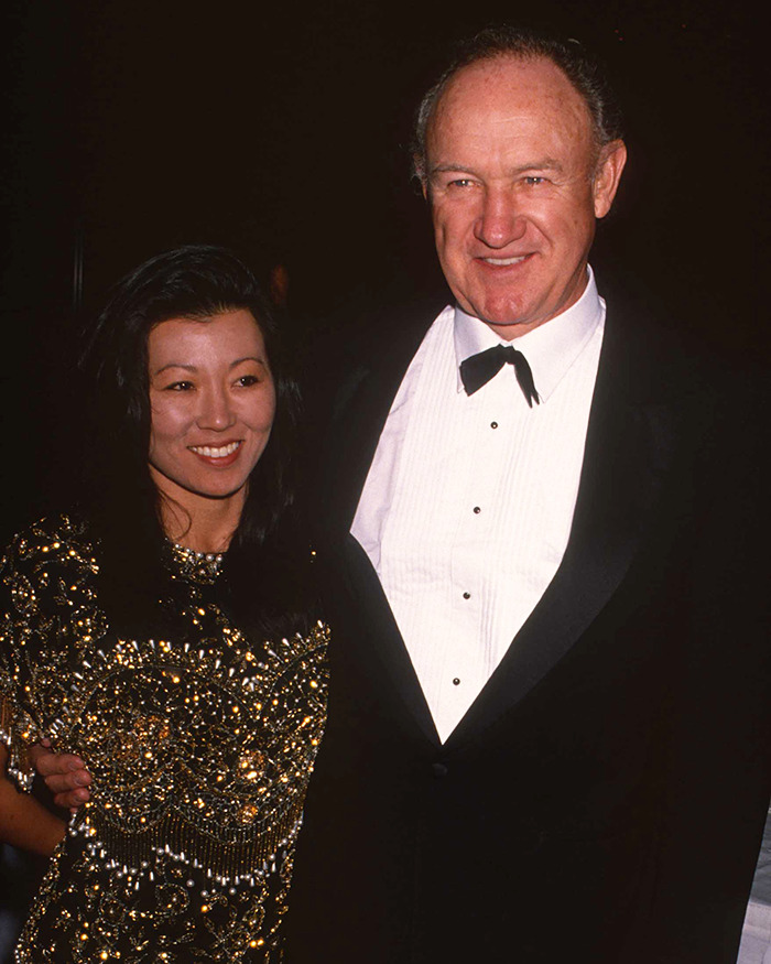 Man in a tuxedo and woman in a sequined dress smiling at an event, related to Gene Hackman handwritten notes discovery.
