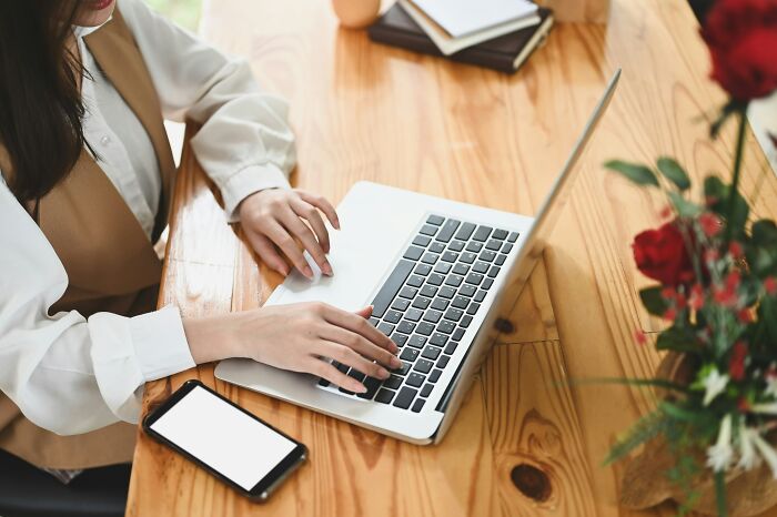 Person typing on a laptop at a wooden table, sharing thoughts about Europe.