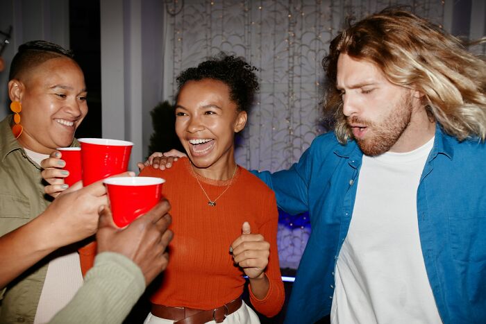 People enjoying a party, holding red cups, showing joy and laughter, emphasizing trusting instincts in social settings.