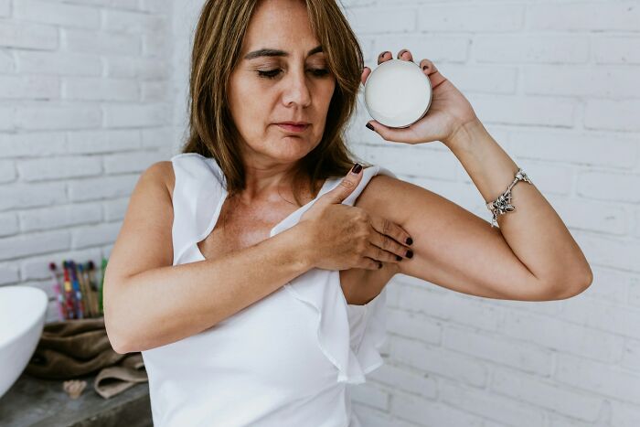 Woman applying deodorant for fresh hygiene in a bathroom setting.