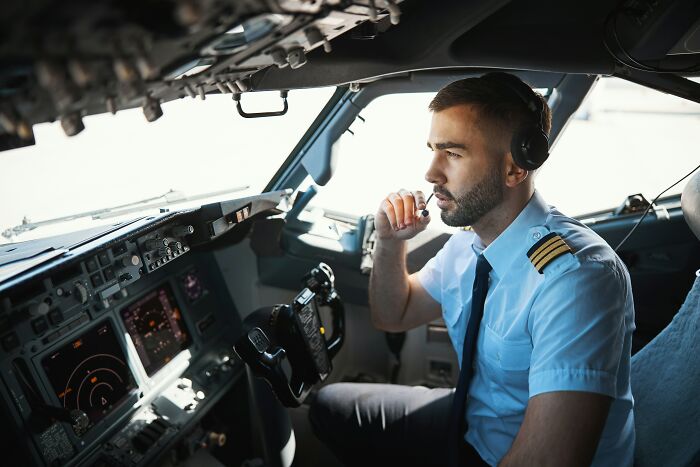 Airline pilot confidently operating cockpit controls, showcasing absolute confidence in flight management.