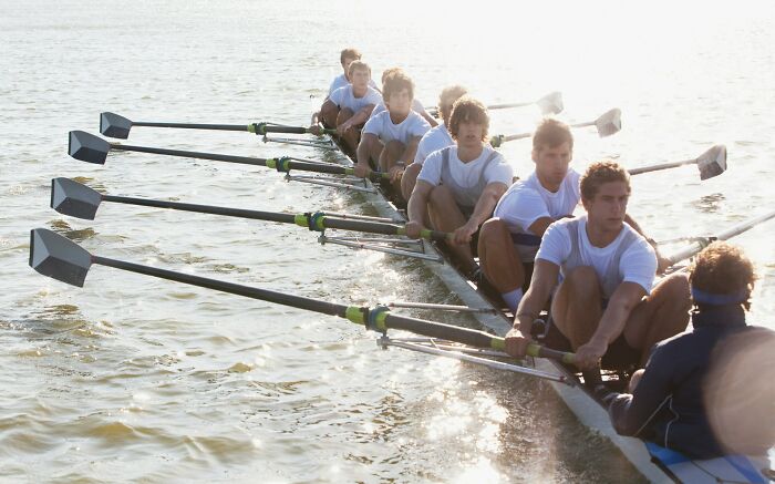 Rowing team in coordinated motion on a sunny day, showcasing teamwork on the water.