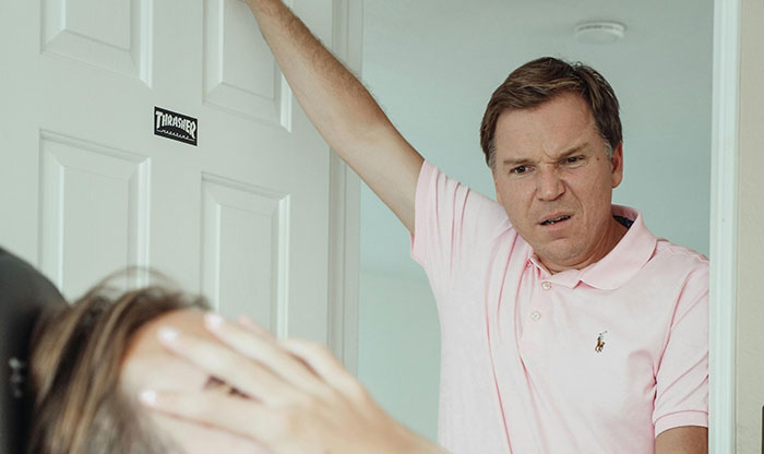 Man expressing frustration in a doorway, highlighting family bond tensions during vacation planning. Man expressing frustration in a doorway, highlighting family bond tensions during vacation planning.
