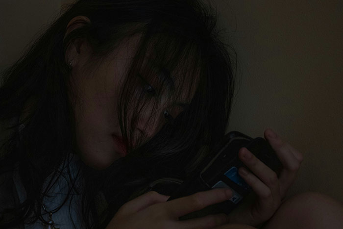 Woman intensely reading a message on her phone, related to man's ex and dates.