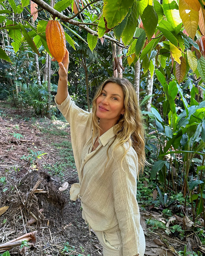 Woman in a cream outfit in a lush garden, standing by a cacao tree in Costa Rica.