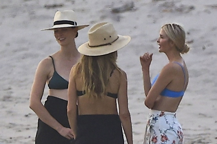 Women on a beach in Costa Rica having a conversation, wearing hats and swimwear.