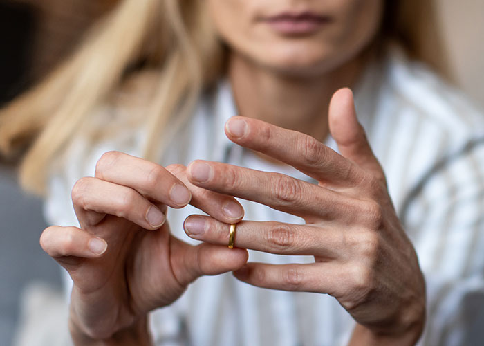Person contemplating with wedding ring, reflecting on phone discoveries and partner relationship changes.