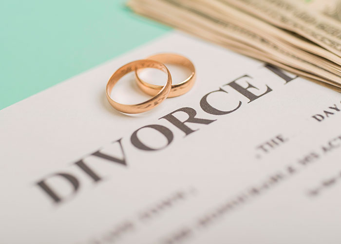 Divorce papers with wedding rings and cash, symbolizing changes in partner perceptions and discoveries.
