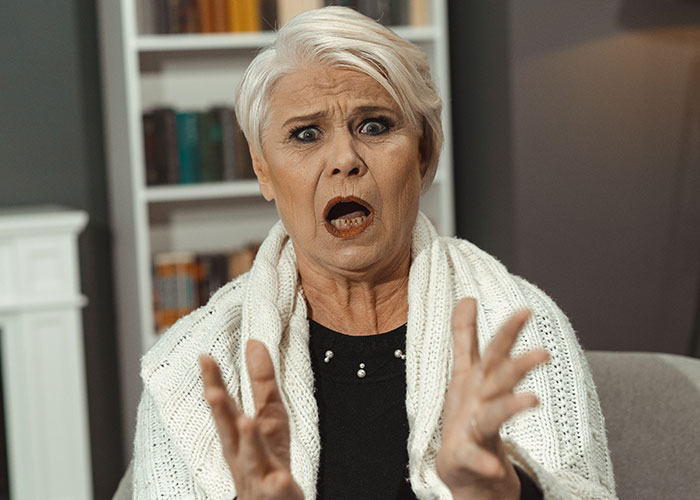 Shocked woman with hands up, expressing surprise, possibly reacting to phone discovery by partner.