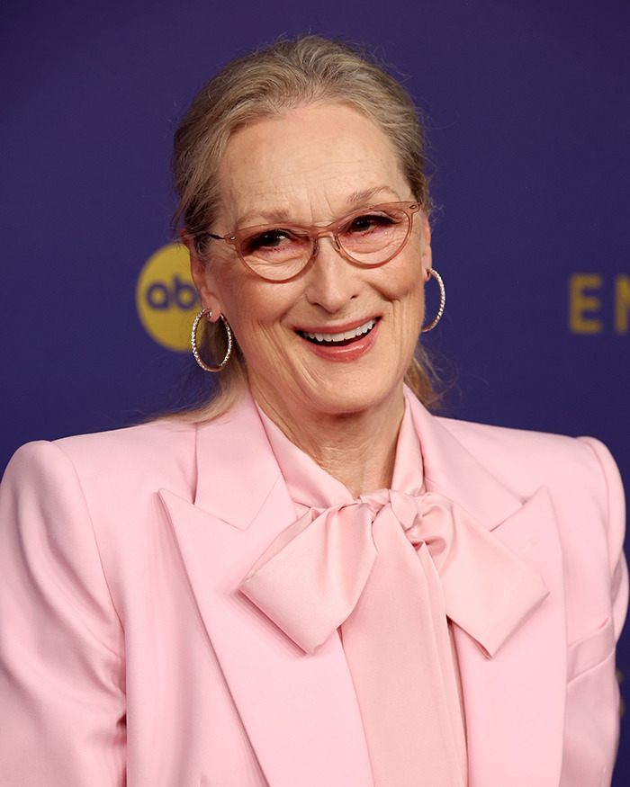 Woman in a pink blazer and glasses smiling at a Narnia reboot event.