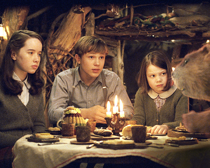 Children from the 'Narnia' reboot sitting at a table with lit candles and food, sparking gender swap rumors.