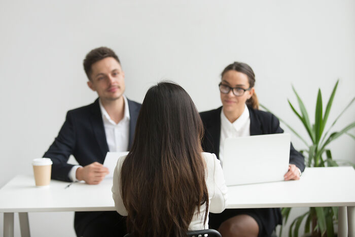 Two interviewers in formal attire with laptops, facing a job candidate, discussing the biggest red flag in job interviews.