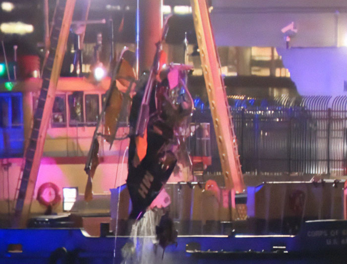 Damaged helicopter wreckage from horrific NYC crash lifted from water at night.