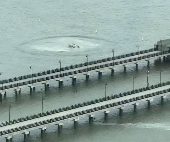 Aerial view of New York helicopter crash in water near bridge, involving tech boss and family.