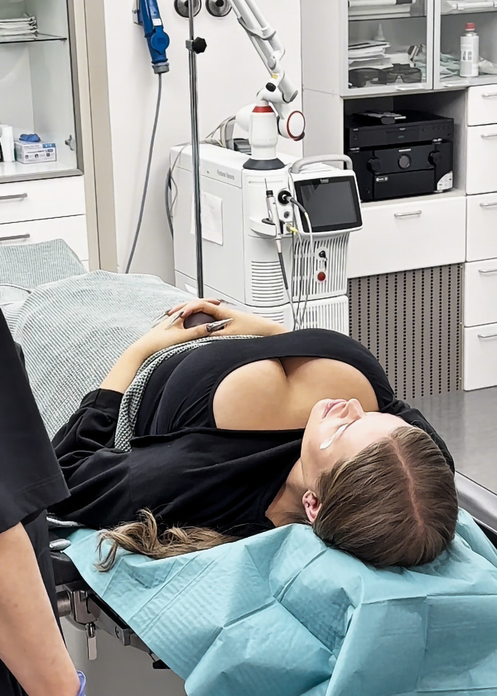 A woman lies in a medical room post-eyelid surgery, covered with a surgical drape. A woman lies in a medical room post-eyelid surgery, covered with a surgical drape.