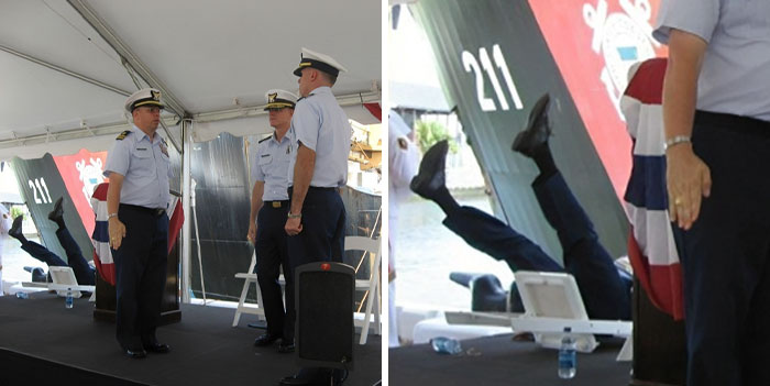 A person in uniform has fallen backwards off a stage during a formal event, legs in the air, while two others watch.