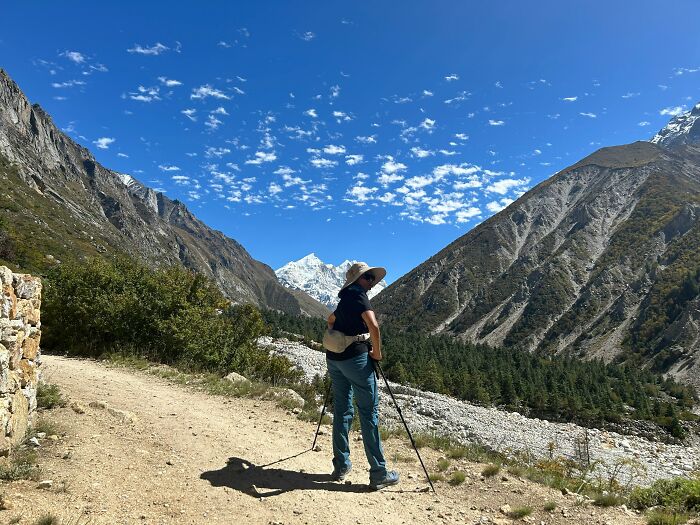 Person hiking in scenic mountains under a clear blue sky, highlighting everyday dangers in outdoor activities.