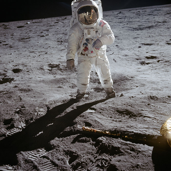 Astronaut walking on the moon, major historical event in space exploration, with shadow and footprints visible on the lunar surface.
