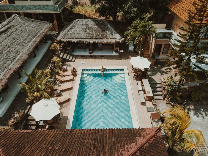 Aerial view of resort pool with families relaxing poolside, enjoying their vacation.