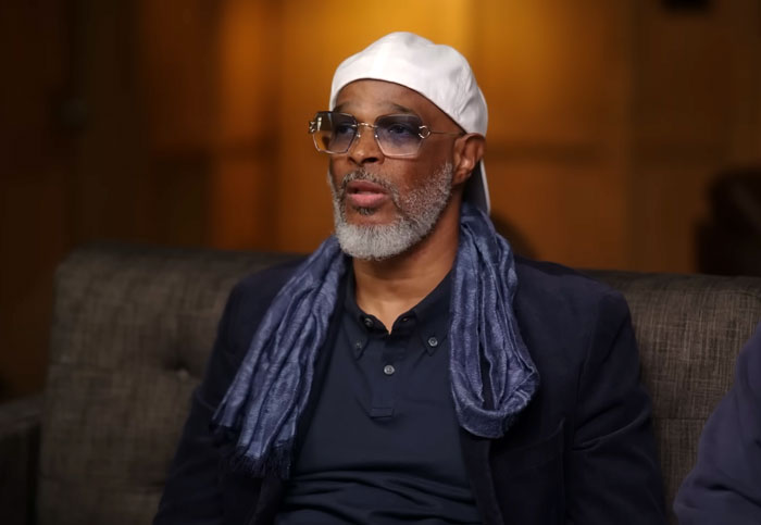 Film legend discusses personal love story, wearing a white hat and glasses in an interview setting.